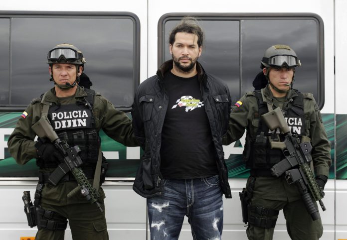 Colombian Erickson Vargas Cardona, center, also known as 'Sebastian,' is escorted by Colombian National Police after being arrested in Girardota on Aug. 8, 2012.