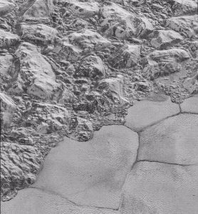 Mountains of water ice cluster on the frozen nitrogen shoreline of Pluto's Sputnik Planitia. (Image: NASA)