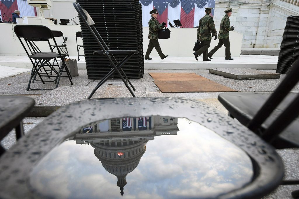The U.S. Capitol is reflected in a water puddle on a chair as people rehearse Sunday for Donald Trump's inauguration. MUST CREDIT: Washington Post photo by Matt McClain